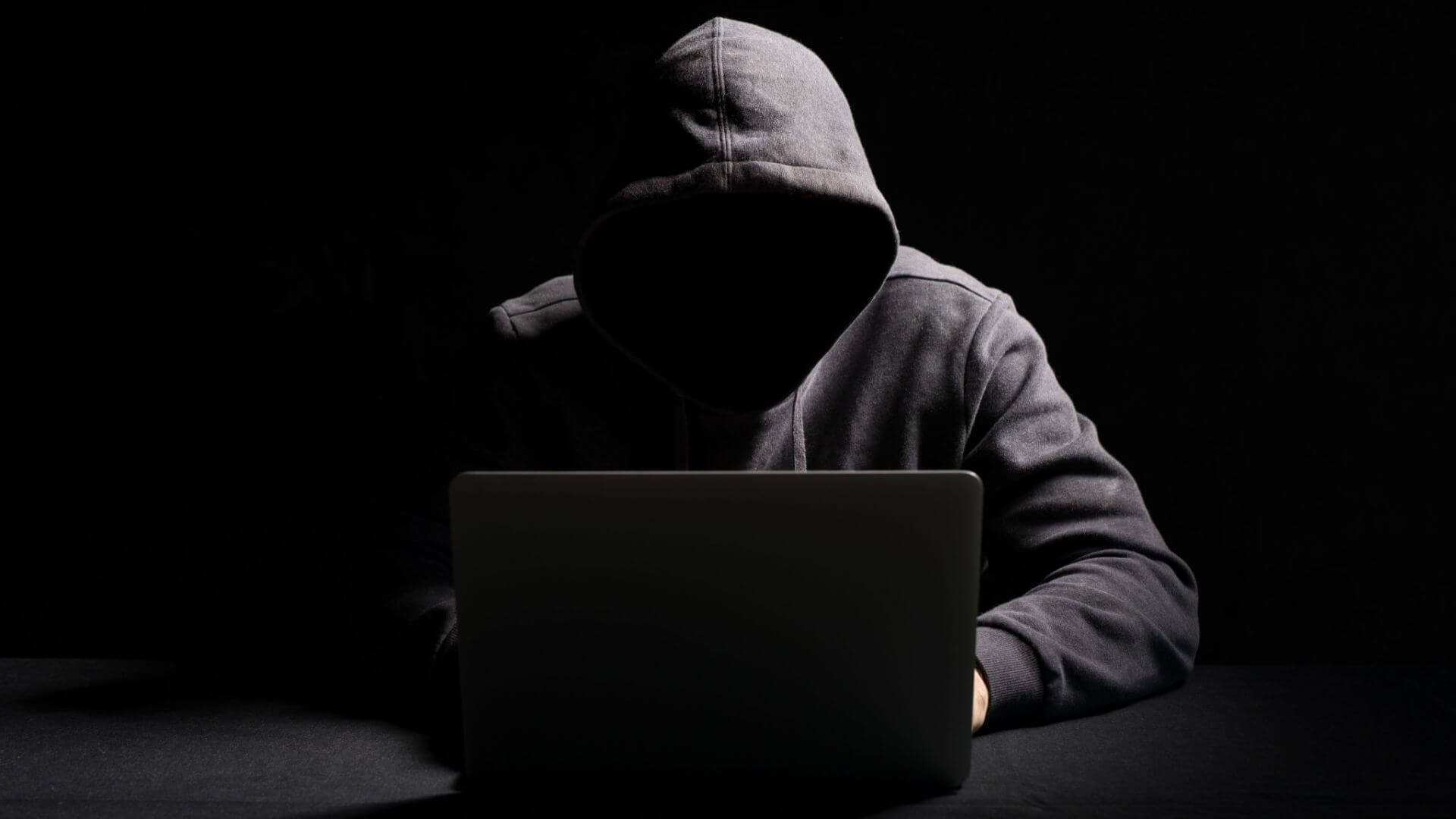 person committing online defamation of another in dark room